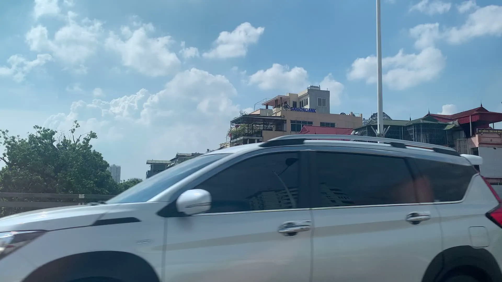 Đây là chuỗi hình ảnh ghi lại quang cảnh đường phố ở Hà Nội, được chụp từ một phương tiện đang di chuyển. Khung cảnh cho thấy những dãy nhà ống cao tầng, san sát nhau, là một đặc trưng của kiến trúc đô thị. Bầu trời trong xanh, có nhiều mây trắng. Trên đường có các phương tiện giao thông như ô tô và xe máy đang di chuyển. Nhiều tòa nhà có các biển hiệu quảng cáo với các nội dung có thể đọc được như sau:。- HDBANK。- Gen Z Sushi Hot pot。- CHACO... & COFFEE。- VietinBank - Nâng giá trị cuộc sống。- ÁC QUY。- EVERON。- Artemis。- PINACO。- NEW LIFE。- Ma Giáo Mart。Hoạt động chính được ghi lại là cảnh giao thông trên một con phố sầm uất với nhiều cửa hàng, ngân hàng và dịch vụ.