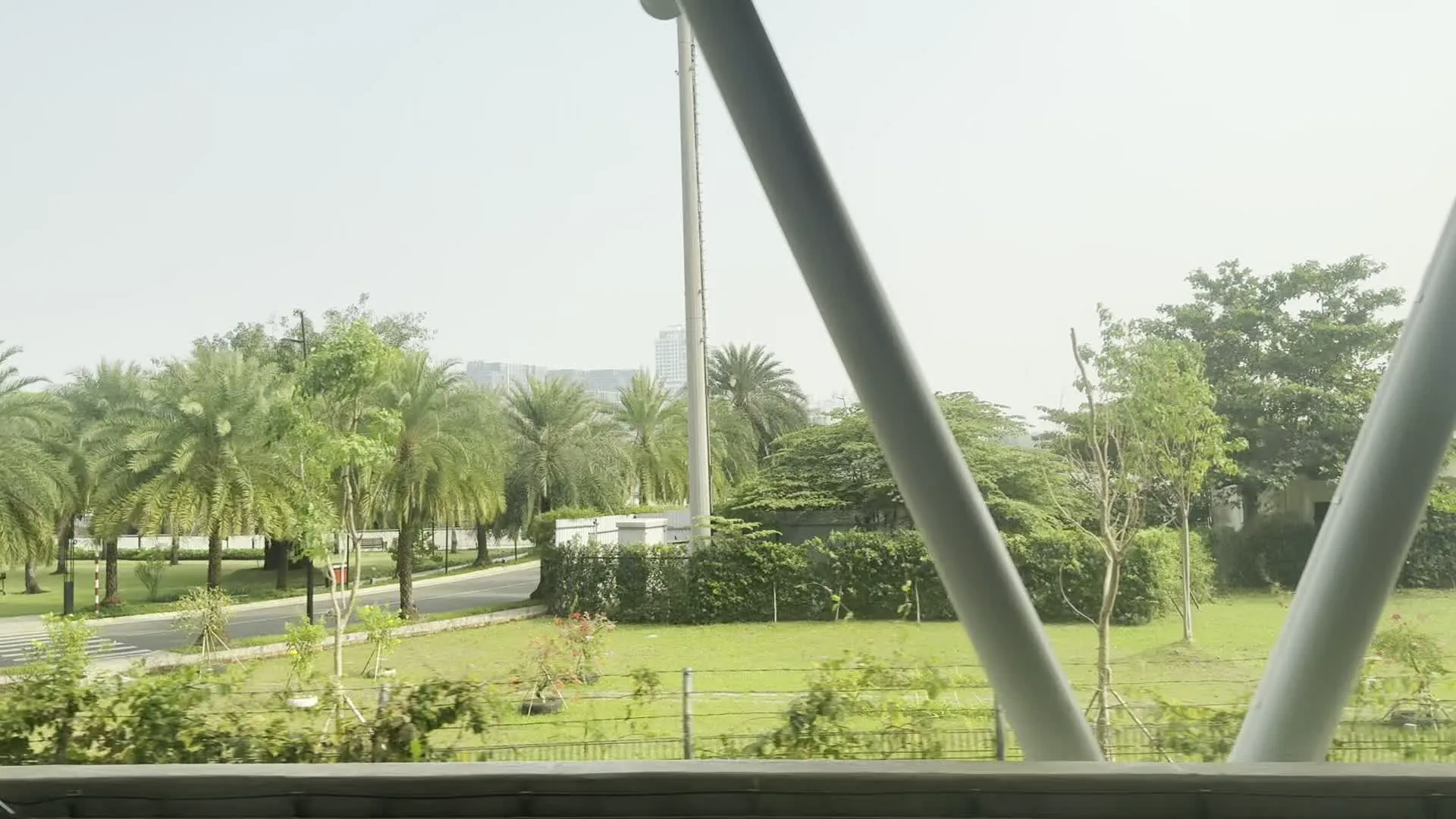 Cảnh quay được ghi lại từ một phương tiện đang di chuyển, có vẻ như là một chuyến tàu điện trên cao. Khung cảnh bên ngoài ban đầu là một khu vực đô thị hiện đại với nhiều cây xanh. Có thể thấy nhiều cây cọ và các loại cây khác được trồng trong một công viên hoặc không gian xanh ven đường, với bãi cỏ và một con đường. Ở phía xa là những tòa nhà cao tầng. Khung cửa sổ của tàu có các thanh đỡ kết cấu màu trắng. Sau đó, con tàu dường như đi vào một đường hầm hoặc đi dọc theo một bức tường bê tông lớn. Trên tường có lắp đặt các đường ống dẫn điện và đèn chiếu sáng. Cảnh vật nhanh chóng trở nên mờ ảo do tốc độ di chuyển của tàu.