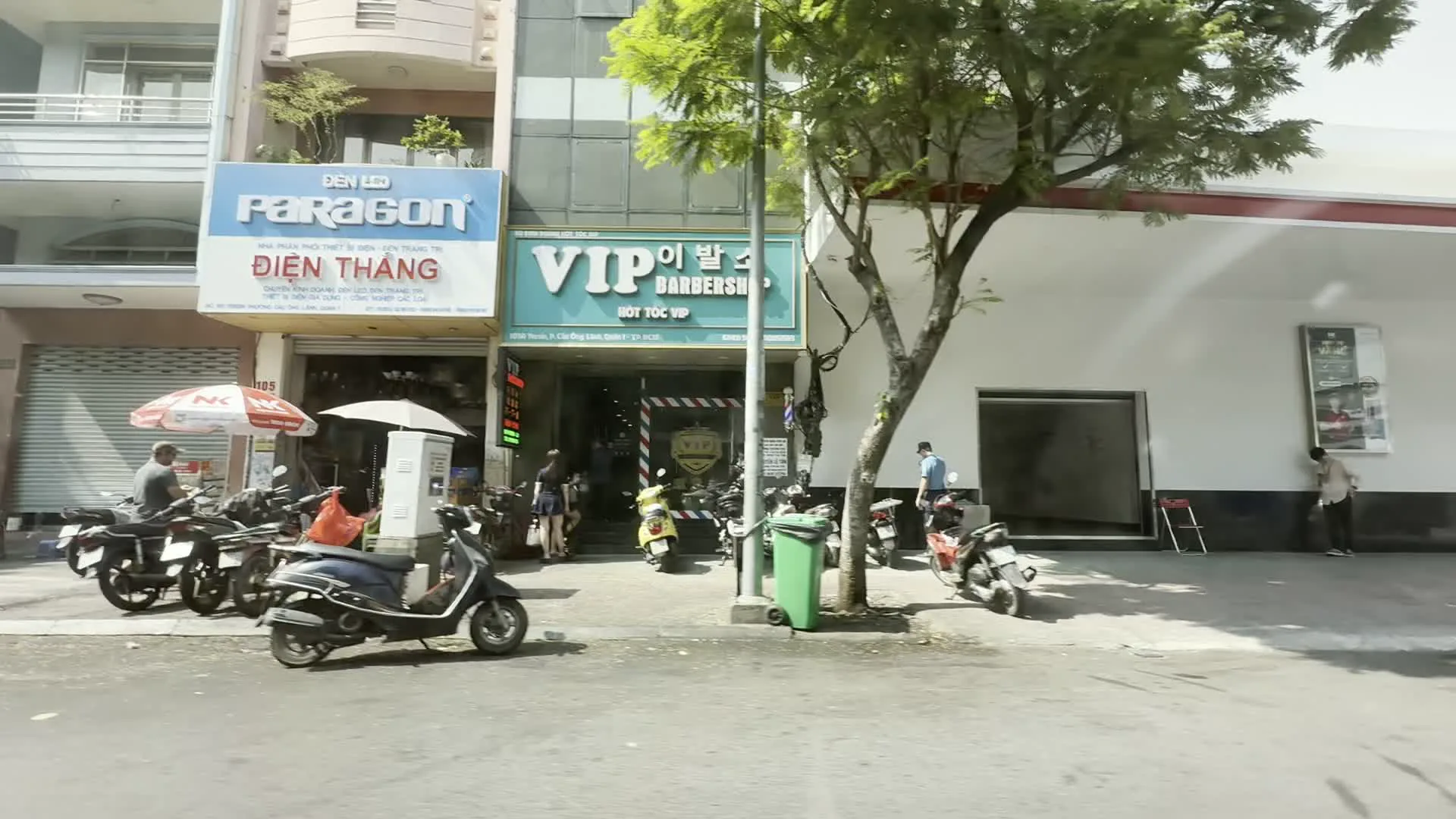 ĐIỆN THẮNG (ディエン・タン / 電気設備・装飾灯の販売店)。VIP BARBERSHOP / HỚT TÓC VIP / 이발소 (VIPバーバーショップ / ベトナム語、英語、韓国語で理髪店を示す看板)。128 Calmette - P. Cầu Ông Lãnh, Quận 1 (ホーチミン市1区カウオンラン坊カルメット通り128番地を示す住所表記)