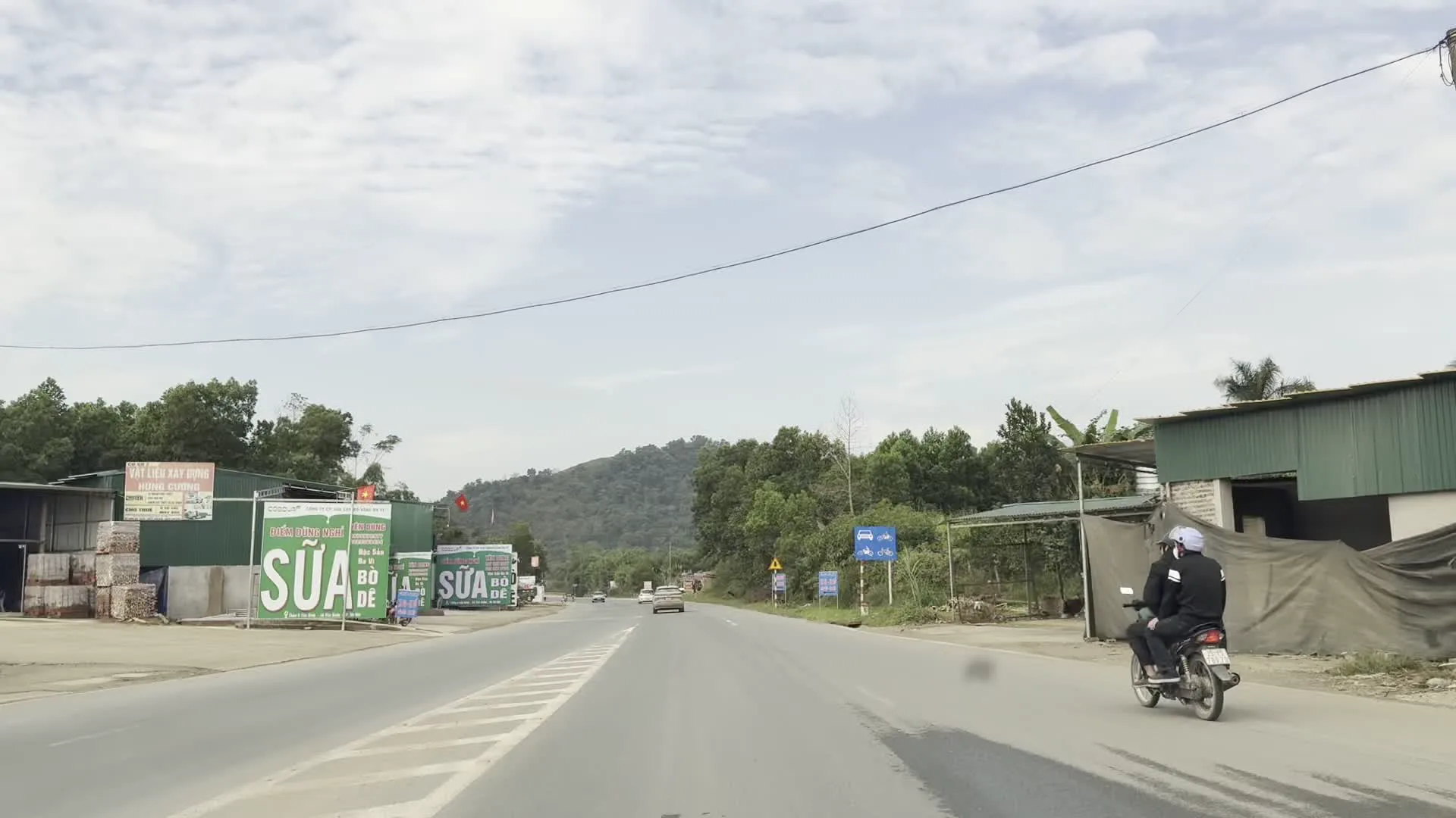 ĐIỂM GIỚI THIỆU VÀ BÁN SẢN PHẨM OCOP, Huyện Lương Sơn（ルオンソン県のOCOP製品紹介・販売所の看板。「OCOP」はベトナムの地域特産品振興プログラム「一村一品運動」）。SỮA BÒ, DÊ（牛乳、ヤギ乳の看板）。MÍA ĐÁ, TÀO PHỚ（サトウキビジュース、豆腐花の看板）。VẬT LIỆU XÂY DỰNG MINH CƯỜNG（ミン・クオン建材店の看板）