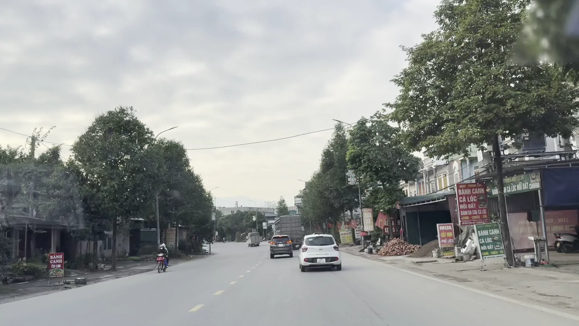 BÁNH CANH CÁ LÓC NỒI ĐẤT / ĐẶC SẢN LỘC SƠN（土鍋の雷魚バインカイン / ロックソン特産品と書かれた飲食店の看板）。CƠM BÌNH DÂN（大衆食堂の看板）