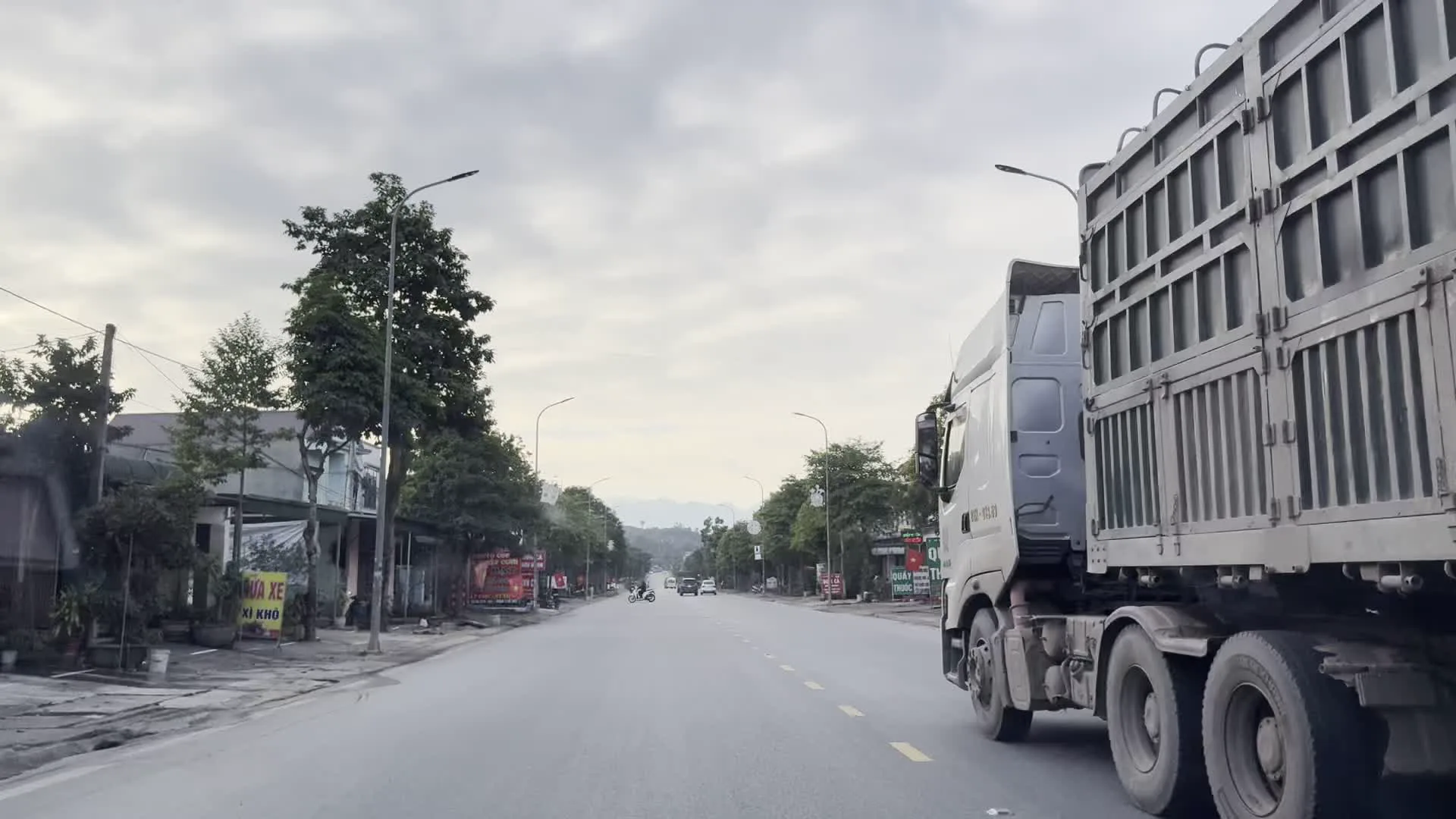 HÀ NỘI 115 km（ハノイまで115kmの道路標識）。Biển báo Thị trấn Phố Vụ Bản, huyện Lạc Sơn（ホアビン省ラックソン県Vụ Bản町の看板）。KÍNH CHÀO QUÝ KHÁCH（お客様、こんにちは / 店舗の歓迎看板）