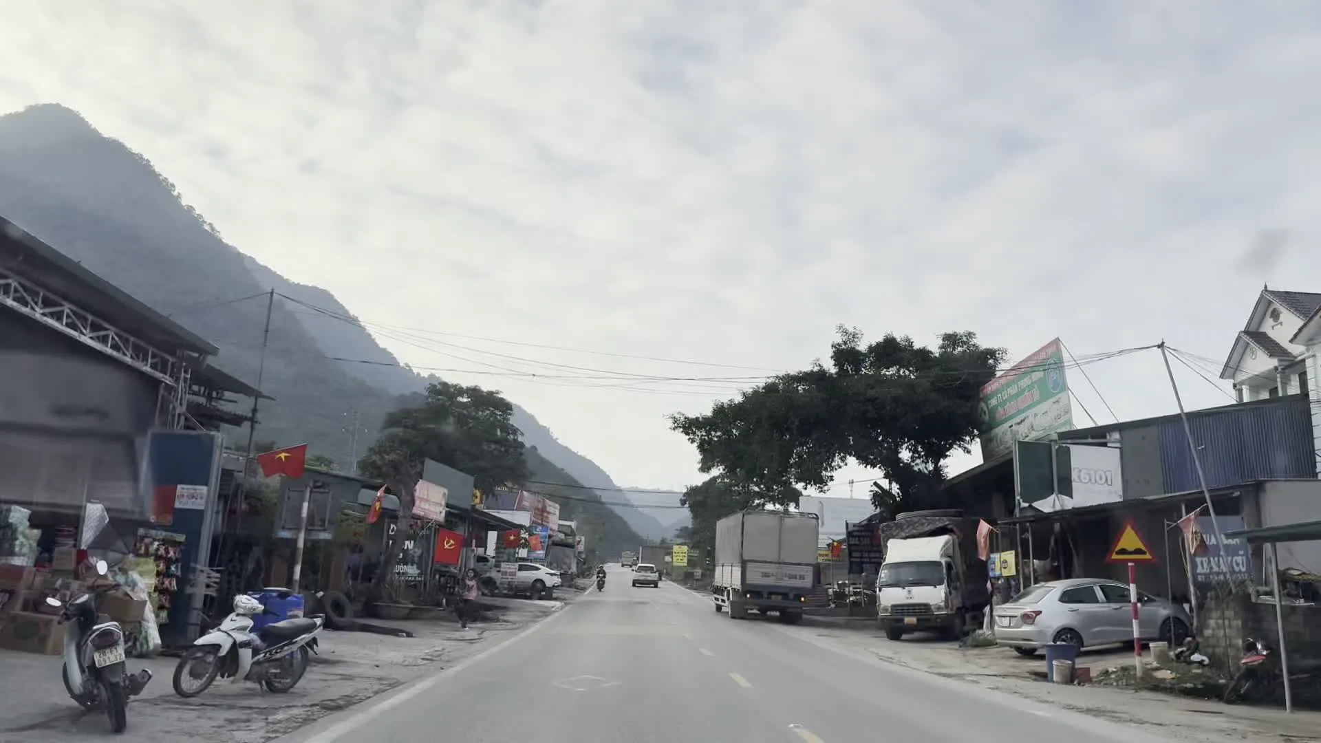 Cột mốc Km 116 trên Quốc lộ 6, chỉ dẫn đi Sơn La 186km (国道6号線上の116km地点キロポスト、ソンラまで186kmを示す)。MÁY NÔNG NGHIỆP (農業機械店の看板)