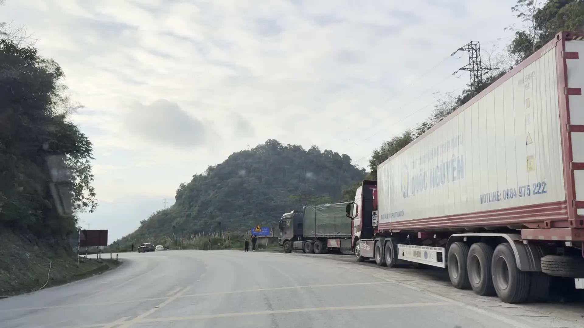 XUỐNG DỐC LIÊN TỤC（連続下り坂の警告標識）。Biển báo nguy hiểm sạt lở đất（落石注意の警告標識）。Xe tải vận chuyển hàng hóa trên Quốc lộ 6（国道6号線を走行する貨物トラック）。Cột cờ Việt Nam（ベトナム国旗）