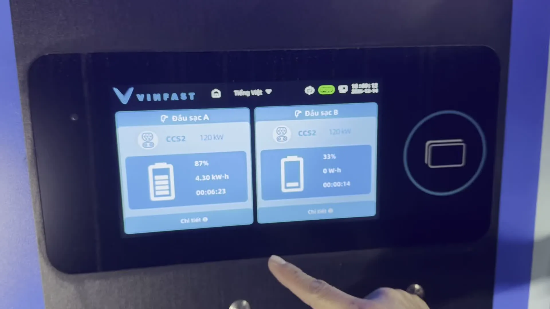 Các hình ảnh cho thấy màn hình cảm ứng của một trạm sạc xe điện VinFast. Một người đang tương tác với màn hình để theo dõi quá trình sạc xe. Ngôn ngữ hiển thị trên màn hình là "Tiếng Việt".。Trong ảnh đầu tiên, màn hình hiển thị hai cổng sạc:。- Đầu sạc A: Chuẩn sạc CCS2 120 kW, mức pin 87%, đã sạc được 4.30 kW-h trong 00:06:23.。- Đầu sạc B: Chuẩn sạc CCS2 120 kW, mức pin 33%, đã sạc được 0 W-h trong 00:00:14.。Các ảnh sau cho thấy màn hình chi tiết của một quá trình sạc. Mức pin tăng từ 34% lên 35%. Các thông số chi tiết được hiển thị bao gồm:。- Năng lượng cung cấp: tăng từ 200 W-h lên 600 W-h.。- Công suất: khoảng 44.3 - 44.5 kW.。- Điện áp: khoảng 427.8 - 429.6 V.。- Dòng điện: khoảng 103.6 A.。Ngày ghi trên màn hình là 14-12-2025.