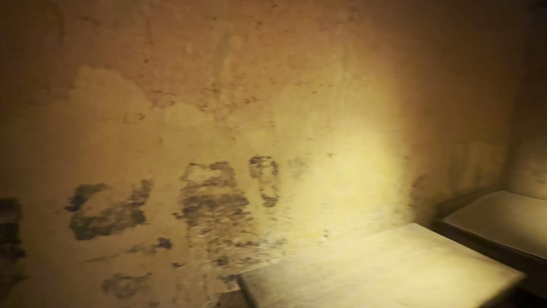 Bối cảnh là không gian bên trong một ngôi nhà truyền thống được tái hiện, có khả năng là một khu trưng bày tại Bảo tàng Dân tộc học Việt Nam. Các bức tường được làm bằng đất, một số chỗ đã bong tróc và có những ký tự hoặc hình vẽ đã mờ, không thể đọc được. Sàn nhà và các cột trụ được làm bằng gỗ.。Trong không gian chính, có một chiếc giường gỗ dài (phản) được đặt sát tường. Ở giữa phòng là một chiếc bàn thấp hình tròn làm bằng mây tre đan, trên bàn có bày một bộ bát đĩa, chén và đũa bằng sứ trắng. Xung quanh bàn là những chiếc đệm ngồi nhỏ được bện từ rơm hoặc cói. Ở góc phòng, có một chiếc ti vi nhỏ kiểu cũ đặt trên một cái kệ gỗ. Ngoài ra còn có một chiếc ấm đun nước bằng kim loại màu đen. Có một tấm biển thông tin bằng gỗ gắn trên tường, nhưng chữ viết trên đó quá nhỏ và mờ để có thể đọc được. Một lối đi dẫn sang một căn phòng khác, bên trong có một bộ bàn ghế gỗ đơn sơ.