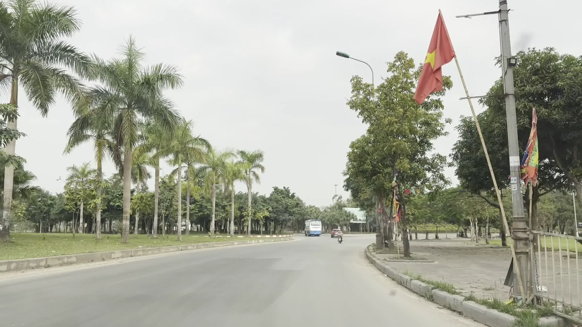 Đoàn kết, đoàn kết, đại đoàn kết. Thành công, thành công, đại thành công.（ホー・チ・ミンの言葉「団結、団結、大団結。成功、成功、大成功。」を記した横断幕）。BÃI ĐỖ XE LÀNG VĂN HÓA（「文化村駐車場」を示す標識。「Làng Văn hóa - Du lịch các dân tộc Việt Nam / ベトナム諸民族文化観光村」の入口駐車場であることを示している）。XE Ô TÔ TỪ 16 CHỖ TRỞ LÊN / XE Ô TÔ DƯỚI 16 CHỖ（16人乗り以上の車と未満の車で進行方向を分ける交通標識）