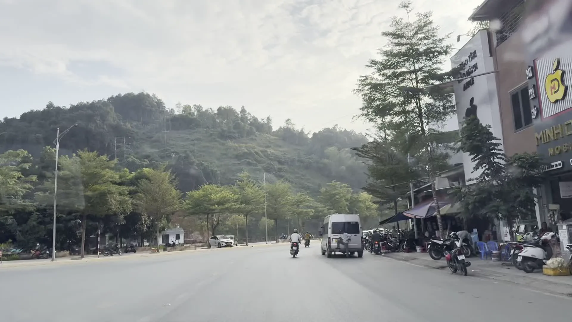 MINH CENTER MOBILE SHOP（携帯電話販売店「ミン・センター・モバイルショップ」）。QUYẾT TÂM THỰC HIỆN THẮNG LỢI NGHỊ QUYẾT ĐẠI HỘI ĐẢNG CÁC CẤP, NHIỆM KỲ 2025 - 2030。（「2025年-2030年任期における各級党大会の決議を勝利裏に実行することを決意する。」と書かれた政治スローガン）。SAPA OPEN TOUR（サパ・オープンツアーの観光バス）