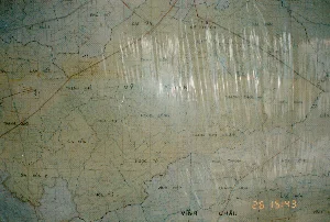 Đây là hình ảnh chụp cận cảnh một tấm bản đồ hành chính của một khu vực thuộc tỉnh Sóc Trăng, được chụp vào năm 1994. Tấm bản đồ được bảo vệ bởi một lớp nhựa trong suốt, gây ra các vệt phản quang trên bề mặt. Trên bản đồ có các thông tin văn bản sau đây:。- Tên các đơn vị hành chính (xã, huyện): PHÚ MỸ, ĐẠI TÂM, MỸ THUẬN, TÀI VĂN, MỸ XUYÊN, TÂN, LÂM KIẾT, THẠNH PHÚ, THAM ĐÔN, VIÊN AN, THẠNH QUỚI, GIA HÒA 1, GIA HÒA 2, HÒA TÚ, HÒA TÚ 2, NGỌC ĐÔNG, NGỌC TỐ, THẠNH THỚI AN, THẠNH THỚI THUẬN, VIÊN BÌNH, LIÊU, HÒA THANH, HÒA ĐÔNG, VĨNH HIỆP, KHÁNH HÒA, LẠC HÒA, VĨNH CHÂU.。- Dấu thời gian kỹ thuật số màu cam ở góc dưới bên phải: "26 15:43".。Bối cảnh và hoạt động: Bức ảnh ghi lại một tấm bản đồ giấy, có thể đang được treo trên tường hoặc trải trên bàn trong một văn phòng hoặc phòng họp để phục vụ công tác nghiên cứu, quy hoạch hoặc chỉ huy. Bản đồ thể hiện chi tiết địa hình với mạng lưới sông ngòi, kênh rạch chằng chịt được biểu thị bằng các đường màu xanh lam, rất đặc trưng cho vùng Đồng bằng sông Cửu Long. Các đường ranh giới hành chính được vẽ bằng nét đứt màu đen và có một số tuyến đường chính được kẻ bằng màu đỏ.。（日本語訳）。これは1994年に撮影された、ソクチャン省に属するある地域の行政地図のクローズアップ写真です。地図は透明なプラスチックの層で保護されており、表面に反射光の筋が生じています。地図上には以下のテキスト情報があります。- 行政単位（社、県）の名称：PHÚ MỸ, ĐẠI TÂM, MỸ THUẬN, TÀI VĂN, MỸ XUYÊN, TÂN, LÂM KIẾT, THẠNH PHÚ, THAM ĐÔN, VIÊN AN, THẠNH QUỚI, GIA HÒA 1, GIA HÒA 2, HÒA TÚ, HÒA TÚ 2, NGỌC ĐÔNG, NGỌC TỐ, THẠNH THỚI AN, THẠNH THỚI THUẬN, VIÊN BÌNH, LIÊU, HÒA THANH, HÒA ĐÔNG, VĨNH HIỆP, KHÁNH HÒA, LẠC HÒA, VĨNH CHÂU。- 右下隅にあるオレンジ色のデジタルタイムスタンプ：「26 15:43」。背景と状況：写真は一枚の紙の地図を写したもので、研究、計画、または指揮の作業のために、オフィスや会議室の壁に掛けられているか、机の上に広げられている可能性があります。地図は、メコンデルタ地域に非常に特徴的な、青い線で示された複雑に絡み合った河川や運河の網の目を持つ地形を詳細に示しています。行政境界線は黒の破線で描かれ、いくつかの主要道路は赤色で引かれています。