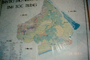 Đây là hình ảnh chụp một tấm bản đồ thổ nhưỡng của tỉnh Sóc Trăng, được treo trên tường. Tấm bản đồ có thể được bọc trong một tấm nhựa trong suốt, gây ra một số phản quang trên bề mặt.。**Chữ viết được ghi lại:**。*   **Tiêu đề chính:** BẢN ĐỒ THỔ NHƯỠNG TỈNH SÓC TRĂNG。*   **Các tỉnh lân cận:** T. CẦN THƠ, T. TRÀ VINH, T. MINH HẢI。*   **Các huyện/thị xã trong tỉnh Sóc Trăng:** KẾ SÁCH, MỸ TÚ, TX SÓC TRĂNG, LONG PHÚ, THẠNH TRỊ, MỸ XUYÊN, VĨNH CHÂU.。*   **Bảng chú dẫn:** Có một bảng "CHÚ DẪN" ở góc dưới bên trái với các cột "TÊN VIỆT NAM", "TÊN LA TINH", và "DIỆN TÍCH (ha)". Nội dung chi tiết trong bảng liệt kê các loại đất nhưng hơi mờ và khó đọc hết.。*   **Dấu thời gian:** Ở góc dưới bên phải có dấu thời gian kỹ thuật số "26 15:31".。**Mô tả cảnh và hoạt động:**。*   **Loại địa điểm:** Bức ảnh dường như được chụp trong một văn phòng, cơ quan chính phủ hoặc viện nghiên cứu, nơi trưng bày các bản đồ kỹ thuật để phục vụ công tác quy hoạch hoặc nghiên cứu nông nghiệp.。*   **Hoạt động:** Hoạt động chính là việc chụp ảnh lại tấm bản đồ thổ nhưỡng. Bản thân tấm bản đồ là một đối tượng tĩnh, cung cấp thông tin về các loại đất khác nhau trong tỉnh Sóc Trăng, được phân biệt bằng màu sắc.。*   **Vật thể trong ảnh:** Đối tượng chính là tấm bản đồ tỉnh Sóc Trăng, thể hiện ranh giới hành chính và phân loại đất đai vào thời điểm năm 1994. Bản đồ được đóng khung và có lớp phủ bảo vệ.。（日本語訳）。これは壁に掛けられているソクチャン省の土壌図を撮影した画像です。この地図は透明なプラスチックシートで覆われている可能性があり、表面にいくつかの光の反射を引き起こしています。**記録されている文字：**。*   **主なタイトル：** ソクチャン省土壌図。*   **隣接する省：** カントー省、チャーヴィン省、ミンハイ省。*   **ソクチャン省内の各県/市社：** ケーサック、ミートゥー、ソクチャン市社、ロンフー、タインチ、ミースエン、ヴィンチャウ。*   **凡例：** 左下隅に「凡例」の表があり、「ベトナム名」、「ラテン名」、「面積（ha）」の列があります。表の詳細な内容は各土壌の種類をリストアップしていますが、少しぼやけており、すべてを読むのは困難です。*   **タイムスタンプ：** 右下隅に「26 15:31」というデジタルタイムスタンプがあります。**場面と活動の説明：**。*   **場所の種類：** この写真は、計画策定や農業研究の業務に役立てるために技術的な地図が展示されているオフィス、政府機関、または研究所で撮影されたようです。*   **活動：** 主な活動は土壌図を撮影することです。地図自体は静的なオブジェクトであり、ソクチャン省内のさまざまな種類の土壌に関する情報を提供し、色によって区別されています。*   **写真の中の物体：** 主な対象は、1994年時点の行政境界と土地の分類を示すソクチャン省の地図です。地図は額装されており、保護用のカバーがかけられています。