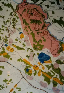 Đây là hình ảnh chụp cận cảnh một tấm bản đồ chi tiết về khu vực huyện Củ Chi và các vùng lân cận. Bản đồ này có vẻ là một bản đồ quân sự hoặc hành chính cũ, thể hiện các địa danh, đơn vị hành chính và các vị trí chiến lược.。Các thông tin bằng chữ có thể đọc được trên bản đồ bao gồm:。- Tên các quận/huyện: QUẬN CỦ CHI, QUẬN TRẢNG BÀNG, QUẬN ĐỨC HÒA, QUẬN BẾN CÁT, QUẬN DẦU TIẾNG.。- Tên các xã: Xã Phước Thạnh, Xã Trung Lập Thượng, Xã Trung Lập Hạ, Xã An Nhơn Tây, Xã Nhuận Đức, Xã Phú Mỹ Hưng, Xã An Phú, Xã Phú Hòa Đông, Xã Tân Thạnh Tây, Xã Tân Thông, Xã Tân An Hội, Xã Phước Hiệp, Xã Đức Hiệp, Xã An Thành.。- Tên các căn cứ và trung tâm huấn luyện: CĂN CỨ ĐỒNG DÙ, TRUNG TÂM HUẤN LUYỆN MŨI LỚN, TRUNG TÂM HUẤN LUYỆN TRUNG HOA, ĐỒN ĐIỀN CAO SU LÝ VĂN MẠNH.。- Tên các địa danh khác: SÔNG SÀI GÒN, RỪNG CÁ CHÚC, SUỐI CỤT, CHỐT ĐỒNG CHÙA, BẦU TRÀI, TL 8A (Tỉnh Lộ 8A).。Bản đồ sử dụng các màu sắc khác nhau để phân biệt các loại địa hình và khu vực: màu xanh lá cây cho rừng rậm, màu hồng và đỏ cho các khu vực căn cứ, màu xanh dương cho sông và các căn cứ lớn (như Căn cứ Đồng Dù), màu vàng cho các khu vực khác. Các đường kẻ đen và đỏ thể hiện mạng lưới giao thông hoặc có thể là hệ thống địa đạo. Ngoài ra còn có các ký hiệu quân sự như cờ và các biểu tượng khác. Ở phía bên trái bức ảnh có các chữ số màu cam "97 7 23", có thể là dấu ngày tháng do máy ảnh ghi lại.。（日本語訳）。これは、クチ県とその周辺地域に関する詳細な地図のクローズアップ写真です。この地図は、地名、行政単位、戦略的地点を示す、古い軍事地図または行政地図のようです。地図上で読み取れる文字情報には、以下のものが含まれます。- 各郡/県の名前：クチ郡、チャンバン郡、ドゥックホア郡、ベンカット郡、ザウティエン郡。- 各社の名前：フオックタイン社、チュンラップトゥオン社、チュンラップハ社、アンニョンタイ社、ニュアンドゥック社、フーミーハン社、アンフー社、フーホアドン社、タンタインタイ社、タントン社、タンアンホイ社、フオックヒエップ社、ドゥックヒエップ社、アンタイン社。- 各基地および訓練センターの名前：ドンズー基地、ムイロン訓練センター、チュンホア訓練センター、リー・ヴァン・マインゴム農園。- その他の地名：サイゴン川、カーチュックの森、スオイカット（小川）、ドンチュア監視所、バウチャイ、TL 8A（省道8A号線）。地図は、地形や地域を区別するためにさまざまな色を使用しています。緑色は密林、ピンクと赤は基地エリア、青は川や大規模な基地（ドンズー基地など）、黄色はその他の地域を示しています。黒と赤の線は交通網を表しているか、あるいは地下トンネル網である可能性もあります。その他にも、旗などの軍事記号やその他のシンボルがあります。写真の左側にはオレンジ色の数字「97 7 23」があり、これはカメラによって記録された日付スタンプである可能性があります。