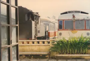 Bối cảnh là một sân ga xe lửa, có khả năng là Ga Đà Lạt. Hai đoàn tàu đang đỗ trên đường ray. Bên trái là một đầu máy xe lửa hơi nước kiểu cũ, màu đen. Bên phải là một toa xe lửa tự hành (railcar) có thiết kế cổ điển, sơn màu kem và đỏ. Phía trước đầu toa xe này có một biểu tượng hình đôi cánh màu vàng, là logo cũ của ngành Đường sắt Việt Nam. Ở phía trước, có một bồn cây bằng xi măng trồng cây lá xanh, đặt dọc theo sân ga. Bức ảnh dường như được chụp từ bên trong một tòa nhà, nhìn qua khung cửa sổ ở phía bên trái. Khung cảnh tĩnh lặng, các đoàn tàu đang dừng bánh.。（日本語訳）。背景は鉄道のプラットフォームで、おそらくダラット駅です。2つの列車が線路上に停車しています。左側は旧式の黒い蒸気機関車です。右側はクラシックなデザインの、クリーム色と赤色に塗装された気動車（レールカー）です。この車両の前面には、ベトナム鉄道の旧ロゴである黄色の翼の形をしたシンボルがあります。手前には、緑の葉の植物が植えられたセメント製のプランターが、プラットフォームに沿って置かれています。この写真は、建物の中から、左側にある窓枠を通して撮影されたようです。静かな光景で、列車は停止しています。