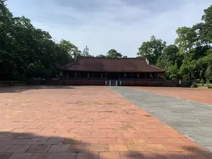 前景には広大な赤レンガ敷きの中庭が広がり。建物は豊かな緑の木々に囲まれています