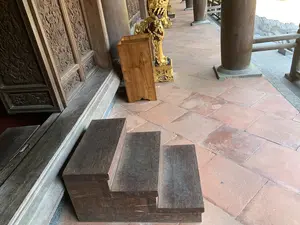 木造建築の縁側。床は赤茶色のタイルで、壁には木彫りが施されている