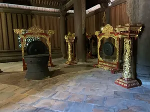 木造建築の内部に、銅鼓と、金と赤で華やかに装飾された台座に吊るされた銅鑼が複数展示されている