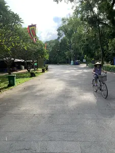 緑豊かな木々に囲まれたラムキン遺跡内の参道。右側にはノンラーをかぶった女性が自転車に乗っている