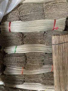 Hình ảnh chụp cận cảnh một chồng lớn các bó chiếu hoặc nguyên liệu dệt chiếu, có thể là chiếu cói, một sản phẩm thủ công truyền thống. Các bó được xếp chồng lên nhau một cách ngay ngắn. Có thể phân biệt được các loại bó khác nhau: một số có màu trắng ngà, trông giống như đã được xử lý, trong khi những bó khác có màu nâu sẫm tự nhiên của vật liệu khô. Các bó này được buộc chặt bằng dây nhựa màu đỏ, xanh lá cây và đen để giữ chúng lại với nhau. Cảnh tượng này cho thấy việc lưu trữ hoặc chuẩn bị nguyên liệu với số lượng lớn, có thể tại một xưởng sản xuất hoặc kho hàng ở một làng nghề chuyên về dệt chiếu, chẳng hạn như ở Nga Sơn.。（日本語訳）。伝統的な手工芸品である、い草のマットと思われる、マットの束またはマット織りの材料の大きな山積みのクローズアップ写真。束はきちんと積み重ねられています。異なる種類の束を区別することができます。いくつかは象牙色で、処理されたように見えますが、一方、他の束は乾燥した素材の自然な濃い茶色をしています。これらの束は、赤、緑、黒のプラスチック製の紐でしっかりと結ばれて、まとめられています。この光景は、例えばガソン（Nga Sơn）のような、マット織りを専門とする工芸村の工房や倉庫で、大量の材料が保管または準備されている様子を示している可能性があります。