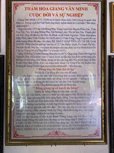 Bức ảnh chụp cận cảnh một tấm bảng thông tin được đóng trong khung kính màu vàng, treo trên tường. Tấm bảng này giới thiệu về cuộc đời và sự nghiệp của danh nhân lịch sử Giang Văn Minh. Toàn bộ văn bản trên bảng được ghi lại như sau:。THÁM HOA GIANG VĂN MINH。CUỘC ĐỜI VÀ SỰ NGHIỆP。Giang Văn Minh (1573-1638) tự là Quốc Hoa, hiệu Văn Chung là quan nhà Hậu Lê. Trong Lịch Sử Việt Nam ông được mệnh danh là vị sứ thần “Bất nhục quân mệnh”.。Ông sinh năm 1573 tại Xã Mông Phụ, Tổng Cam Giá, Huyện Phúc Lộc, Tỉnh Sơn Tây. Nay là Làng Mông Phụ, Xã Đường Lâm, Thị xã Sơn Tây, Thành phố Hà Nội. Ông đỗ đầu kỳ thi Hội, thi Đình và đỗ Đình Nguyên, Thám Hoa khoa Mậu Thìn, năm Vĩnh Tộ thứ 10 (1628) đời Lê Thần Tông. Ông là người đỗ cao nhất trong khoa thi này với chức ĐỆ NHẤT GIÁP TIẾN SĨ CẬP ĐỆ TAM DANH- Hiện còn lưu giữ tại văn bia số 32 Văn Miếu - Quốc Tử Giám Hà Nội.。Sau khi thi đỗ, ông lần lượt được bổ nhiệm vào các chức vụ như Binh Khoa Đô Cấp Sự Trung (1630) Thái Bộc Tự Khanh (1631).。Ngày 30 tháng 12 năm Dương Hòa thứ 3 (1637), Ông cùng Thiên Đô Ngự Sử Nguyễn Duy Hiểu được vua cử làm Chánh sứ dẫn đầu hai đoàn sứ bộ sang cầu phong và tuế cống nhà Minh. Đoàn sứ bộ của ông đến Yên Kinh (nay là Bắc Kinh) vào năm 1638. Khi vào triều kiến Minh Tư Tông Chu Do Kiểm (tức Hoàng đế Sùng Trinh) ngạo mạn ra cho sứ bộ một vế đối như sau:。“Đồng trụ chí kim đài dĩ lục”。Nghĩa là: Cột đồng đến nay rêu đã xanh.。Câu này hàm ý nhắc tới việc Mã Viện từng đàn áp cuộc khởi nghĩa Hai Bà Trưng, sau đó cho chôn một chiếc cột đồng với lời nguyền : “Đồng trụ chiết giao chỉ diệt” (Cột đồng gãy thì Giao Chỉ- tức Đại Việt- bị diệt vong).。Trước sự ngạo mạn đó- Ông đã hiên ngang đối lại bằng câu:。“Đằng giang tự cổ huyết do hồng”。Nghĩa là: Sông Đằng từ xưa máu còn đỏ.。Vế đối này vừa chỉnh, vừa có ý nhắc lại việc người Việt đã ba lần đánh tan quân xâm lược phương Bắc trên sông Bạch Đằng. Vua nhà Minh bừng bừng lửa giận nên quên mất thể diện thiên triều, bất chấp luật lệ bang giao đã trả thù bằng cách... ám đường vào miệng và mắt ông rồi cho người mổ bụng xem “Lọn sứ thần An Nam to gan lớn mật đến đâu”. Sự việc này xảy ra vào ngày mùng 2 tháng 6 năm Kỷ Mão, nhưng Minh Tư Tông vẫn kính trọng ông, cho ướp xác bằng bột thủy ngân và đưa thi hài ông về nước.。Khi thi hài của ông về đến Kinh thành Thăng Long, vua Lê Thần Tông và chúa Trịnh Tráng bái kiến linh cữu ông và truy tặng chức CÔNG BỘ TẢ THỊ LANG, TƯỚC VINH QUẬN CÔNG ban tặng câu “SỨ BẤT NHỤC QUÂN MỆNH, KHẢ VỊ THIÊN CỔ ANH HÙNG” tức là: SỨ THẦN KHÔNG LÀM NHỤC MỆNH VUA, XỨNG ĐÁNG LÀM ANH HÙNG THIÊN CỔ.。（日本語訳）。黄色いガラスの額縁に入れられ、壁に掛けられた案内板のクローズアップ写真。この案内板は、歴史上の偉人であるジャン・ヴァン・ミンの生涯と功績について紹介している。板に書かれた全文は以下の通りである。探花 ジャン・ヴァン・ミン。生涯と功績。ジャン・ヴァン・ミン（1573-1638）、字はクオック・ホア、号はヴァン・チュンは、後黎朝の官吏である。ベトナムの歴史において、彼は「君命を辱めず」の使節として知られている。彼は1573年、ソンタイ省フックロック県カムザー総モンフー社に生まれた。現在はハノイ市ソンタイ市社ドゥオンラム社モンフー村である。彼は会試、殿試で首席となり、黎神宗の治世、永祚10年（1628年）の戊辰科で殿元、探花に及第した。彼はこの科挙で最高位の合格者であり、その官職は「第一甲進士及第第三名」であった。これは現在、ハノイの文廟・國子監の32番の石碑に記録が残されている。科挙に合格した後、彼は兵科都給事中（1630年）、太僕寺卿（1631年）などの官職に次々と任命された。陽和3年（1637年）12月30日、彼は都御史のグエン・ズイ・ヒエウと共に、王から正使に任命され、二つの使節団を率いて明朝への冊封と朝貢のために派遣された。彼の使節団は1638年に燕京（現在の北京）に到着した。明の思宗朱由検（崇禎帝）に謁見した際、傲慢にも使節団に次のような対句の上句を出した。「銅柱至今苔已緑」。意味：銅の柱は今日に至るまで苔で青々としている。この句は、馬援がかつてハイ・バー・チュンの反乱を鎮圧し、その後「銅柱折交趾滅」（銅柱が折れる時、交趾、すなわち大越は滅びる）という呪いの言葉と共に銅柱を立てたことを暗に示している。その傲慢さに対し、彼は堂々と次の句で返した。「藤江自古血猶紅」。意味：バクダン川は昔から血でまだ赤い。この対句の下句は、対として完璧であるだけでなく、ベトナム人がバクダン川で三度にわたり北からの侵略軍を打ち破ったことを思い起こさせる意図があった。明の皇帝は激怒し、天朝の体面を忘れ、外交上の慣例を無視して報復した。それは…彼の口と目に毒を流し込み、そして人に命じて腹を裂かせ、「度胸のある安南の使節の肝がどれほど大きいか」見させたのである。この事件は己卯年6月2日に起こったが、明の思宗はそれでも彼を敬い、遺体を水銀の粉末で防腐処理し、本国へ送還させた。彼の遺体が都タンロンに帰還すると、黎神宗帝と鄭主鄭梉は彼の棺に拝謁し、工部左侍郎の職と栄郡公の爵位を追贈し、「使不辱君命、可謂千古英雄」という句を賜った。すなわち、「君命を辱めぬ使節、千古の英雄に値する」という意味である。