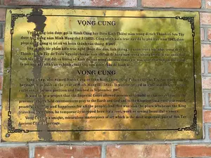 Bức ảnh chụp cận cảnh một tấm biển thông tin bằng đồng được gắn trên một bức tường gạch tại di tích Thành cổ Sơn Tây. Tấm biển có khắc chữ giới thiệu về lịch sử của Vọng Cung bằng cả tiếng Việt và tiếng Anh. Một số phần của tấm biển bị ố hoặc hư hỏng nhẹ.。Nội dung chữ viết tiếng Việt được ghi lại đầy đủ như sau:。'VỌNG CUNG。Vọng Cung (còn được gọi là Hành Cung hay Điện Kính Thiên) nằm trong di tích Thành cổ Sơn Tây được xây dựng năm Minh Mạng thứ 3 (1822). Công trình kiến trúc này đã bị phá hủy năm 1947, được phục dựng đúng vị trí cũ và hoàn thành vào tháng 9/2007.。Đây là một tác phẩm kiến trúc nghệ thuật độc đáo, linh thiêng và quan trọng bậc nhất trong di tích Thành cổ Sơn Tây do Triều Nguyễn cho các tỉnh xây cất để hằng năm trong những kỳ đại lễ các quan đầu tỉnh tổ chức tế trời đất và hướng về Kinh đô, cầu mong cho mưa thuận gió hòa, quốc thái dân an. Đây cũng là nơi mỗi khi nhà Vua vi hành, tuần thú tạm dừng chân để hành lễ.'。（日本語訳）。ソンタイ（山西）城趾遺跡にあるレンガの壁に取り付けられた銅製の情報看板のクローズアップ写真。看板には、望宮（Vọng Cung）の歴史を紹介する文字がベトナム語と英語の両方で刻まれている。看板の一部の箇所は、染みがついているか、または軽く損傷している。ベトナム語で書かれた内容は、以下の通り全文が記録されている：。「望宮（VỌNG CUNG）。望宮（行宮（Hành Cung）または敬天殿（Điện Kính Thiên）とも呼ばれる）は、ソンタイ（山西）城趾遺跡内にあり、明命（ミンマン）3年（1822年）に建設された。この建築物は1947年に破壊されたが、元の場所に正確に復元され、2007年9月に完成した。これは、阮（グエン）朝が各省に建設させた、ソンタイ（山西）城趾遺跡の中で最も独特で、神聖で、重要な芸術建築作品である。毎年の大祭の際に各省の長官が天地を祀る儀式を執り行い、都に向かって雨順風和、国泰民安を祈願するためのものであった。ここはまた、国王が行幸、巡幸するたびに儀式を執り行うために一時的に立ち寄る場所でもあった。」