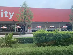 Bức ảnh chụp phía trước một tòa nhà lớn màu đỏ, có khả năng là một siêu thị.。**Chữ viết được ghi lại:**。*   Trên biển hiệu chính của tòa nhà: Chữ trắng lớn "...ity".。*   Trên tường bên dưới mái hiên: "XIN CHÀO", "BÁNH", "NHANH", "SIÊU THỊ".。*   Trên các tấm biển quảng cáo: "GIÁ SỐC".。*   Trên những chiếc ô (dù): logo "-City".。**Mô tả cảnh vật và hoạt động:**。*   **Loại địa điểm:** Đây là một siêu thị hoặc trung tâm mua sắm, được nhận diện qua chữ "SIÊU THỊ" và quy mô của tòa nhà.。*   **Hoạt động:** Nhiều xe máy đang được đậu ở khu vực đỗ xe phía trước, cho thấy hoạt động mua sắm đang diễn ra. Một người đội mũ bảo hiểm màu hồng đang ngồi trên xe máy và nhìn vào điện thoại.。*   **Các vật thể:** Tòa nhà siêu thị lớn màu đỏ, nhiều xe máy, một người đang ngồi trên xe máy, các cây ô che nắng màu đỏ và trắng, các biển quảng cáo, cây xanh và bụi rậm ở phía trước.。（日本語訳）。写真は、大きな赤い建物の前で撮られたもので、スーパーマーケットである可能性があります。**記録されている文字：**。*   建物のメインの看板には：大きな白い文字で「...ity」。*   軒下の壁には：「XIN CHÀO」、「BÁNH」、「NHANH」、「SIÊU THỊ」。*   広告看板には：「GIÁ SỐC」。*   傘（パラソル）の上には：「-City」のロゴ。**風景と活動の説明：**。*   **場所の種類：**「SIÊU THỊ」という文字と建物の規模から、ここはスーパーマーケットまたはショッピングセンターであると識別されます。*   **活動：**多くのバイクが前の駐車エリアに停められており、買い物の活動が行われていることを示しています。ピンクのヘルメットをかぶった一人の人がバイクに座って携帯電話を見ています。*   **物体：**大きな赤いスーパーマーケットの建物、多くのバイク、バイクに座っている一人の人、赤と白の日よけ傘、広告看板、前方にある緑の木々と茂み。