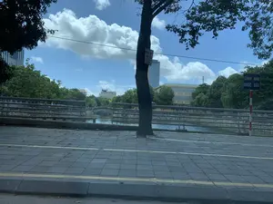 Trong ảnh có các dòng chữ sau: trên thân cây có một biển quảng cáo ghi 'CÔNG TY [chữ không rõ] THANH AN, DIỆT MỐI TẬN GỐC' và số điện thoại '0911511848'; ở bên phải có một biển báo 'CẢNH BÁO NƯỚC SÂU' trên cột sơn sọc đỏ trắng. Bối cảnh là một khu vực đô thị vào ban ngày, nhìn từ vỉa hè ra một con kênh hoặc sông nhỏ. Vỉa hè được lát gạch và có vạch kẻ vàng. Dọc bờ kênh có lan can kim loại bảo vệ, và bờ kênh được kè bằng đá. Phía bên kia kênh là cây cối xanh tươi, một cây cầu vòm nhỏ ở phía xa, và nhiều tòa nhà, trong đó có một tòa nhà cao tầng hiện đại. Bầu trời trong xanh và có nhiều mây. Khung cảnh tĩnh lặng, không có hoạt động cụ thể nào của con người được ghi lại.。（日本語訳）。写真には以下の文字があります：木の幹には「CÔNG TY [不明な文字] THANH AN, DIỆT MỐI TẬN GỐC」と電話番号「0911511848」が書かれた広告看板があります。右側には、赤と白の縞模様に塗られた柱に「CẢNH BÁO NƯỚC SÂU」という標識があります。背景は日中の都市部で、歩道から小さな運河または川を眺めています。歩道はタイルで舗装され、黄色の線が引かれています。運河の岸に沿って金属製の保護手すりがあり、岸は石で護岸されています。運河の向こう側には緑豊かな木々、遠くに小さなアーチ橋、そして近代的な高層ビルを含む多くの建物があります。空は青く澄んでおり、多くの雲があります。静かな光景で、人間の具体的な活動は記録されていません。