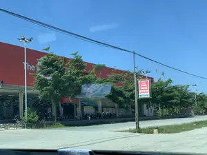 Bức ảnh chụp một siêu thị hoặc trung tâm thương mại lớn có mặt tiền màu đỏ, dưới bầu trời trong xanh. Trên tường của tòa nhà có dòng chữ lớn màu trắng "The GO。". Phía trước tòa nhà là một bãi đậu xe, nơi có rất nhiều xe máy đang được đỗ, cho thấy mọi người có thể đang ở bên trong để mua sắm. Dọc theo khu vực này có trồng nhiều cây xanh và lắp đặt các cột đèn cao áp. Ở phía trước, có một biển báo giao thông được treo trên cột với nội dung tuyên truyền: "ĐÃ UỐNG RƯỢU, BIA - KHÔNG LÁI XE" và "HÃY NÓI KHÔNG VỚI RƯỢU, BIA KHI THAM GIA GIAO THÔNG". Khung cảnh cho thấy một khu vực thương mại ven đường vào một ngày nắng.。（日本語訳）。青空の下、赤いファサードを持つ大きなスーパーマーケットまたはショッピングセンターを写した写真です。建物の壁には「The GO。」という大きな白い文字があります。建物の前には駐車場があり、そこにはたくさんのバイクが停められており、人々が中で買い物をしている可能性があることを示しています。このエリアに沿って、多くの緑の木が植えられ、高圧街灯が設置されています。手前には、柱に交通標識が掲げられており、「飲酒したら運転しない」「交通参加時は飲酒にノーと言おう」という啓発内容が書かれています。晴れた日の道沿いの商業エリアの光景です。