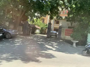 Bức ảnh chụp lối vào của một tòa nhà công vụ dưới bóng cây. Trên mặt tiền tòa nhà có dòng chữ đỏ 'CHI CỤC THI HÀNH ÁN DÂN SỰ'. Bên phải cổng vào, trên tường có một tấm biển màu đỏ với chữ vàng, có thể đọc được là 'CHI CỤC THI HÀNH ÁN DÂN SỰ HUYỆN ĐÔNG SƠN'. Tòa nhà là một công trình nhiều tầng, sơn màu vàng, có treo cờ Việt Nam. Lối vào có một cổng lớn với hai cột trụ bằng đá. Có một vài chiếc ô tô đang đỗ, một chiếc ở bên ngoài lề đường và một chiếc khác ở bên trong sân. Ven đường có nhiều cây xanh lớn, tán lá xum xuê tạo bóng mát xuống mặt đường. Một phần của một chiếc xe máy cũng có thể được nhìn thấy ở phía bên phải của bức ảnh.。（日本語訳）。木陰にある官公庁の建物の入り口を撮影した写真です。建物の正面には「CHI CỤC THI HÀNH ÁN DÂN SỰ」という赤い文字があります。入り口の門の右側、壁には「CHI CỤC THI HÀNH ÁN DÂN SỰ HUYỆN ĐÔNG SƠN」と読める、金色の文字が書かれた赤い看板があります。建物は黄色に塗られた多層建築で、ベトナムの国旗が掲げられています。入り口には石造りの2本の柱がある大きな門があります。数台の車が駐車しており、1台は路肩に、もう1台は敷地内にあります。道端には大きな緑の木々が多く、青々とした葉が路面に影を落としています。写真の右側には、バイクの一部も見えます。