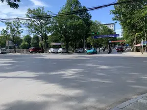 Trong ảnh là một ngã tư hoặc một con đường rộng ở thành phố vào một ngày nắng. Hai bên đường có nhiều cây xanh lớn. Trên đường, các phương tiện giao thông như ô tô và xe máy đang di chuyển. Một số ô tô đang đỗ ở khu vực cho phép bên lề đường, được chỉ dẫn bởi biển báo chữ 'P'. Đèn tín hiệu giao thông đang bật màu xanh với số đếm ngược là '04'. Ở phía xa có thể thấy các tòa nhà cao tầng. Vắt ngang qua đường có treo các băng rôn. Một băng rôn lớn có nội dung: 'CHÀO MỪNG ĐẠI BIỂU THAM DỰ LIÊN HOAN PHÁT THANH TOÀN QUỐC LẦN THỨ XVI - 2024. Thanh Hóa, ngày 09 - 14/7/2024'. Một băng rôn khác có nội dung 'NÂNG CAO CHẤT LƯỢNG BẢO VỆ PHÁT TRIỂN ĐẤT NƯỚC NHANH VÀ BỀN VỮNG。'. Một biển báo màu xanh cho biết tên đường là 'ĐƯỜNG TRIỆU QUỐC ĐẠT'.。（日本語訳）。道路の両側には大きな緑の木がたくさんあります。道路では、自動車やバイクなどの交通車両が移動しています。いくつかの車が、「P」の文字の標識で示された路肩の許可されたエリアに駐車しています。交通信号は青色で、カウントダウンの数字は「04」です。遠くには高層ビルが見えます。道路を横切って横断幕が掲げられています。大きな横断幕には「第16回全国ラジオフェスティバル - 2024に参加する代表者を歓迎します。タインホア、2024年7月9日～14日」と書かれています。もう一つの横断幕には「国の迅速かつ持続可能な発展と保護の質を向上させる。」と書かれています。青い標識は、通りの名前が「TRIỆU QUỐC ĐẠT通り」であることを示しています。