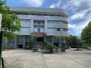 Bức ảnh chụp một tòa nhà văn phòng nhiều tầng, hiện đại, là một cơ quan hành chính ở Thanh Hóa. Trên mặt tiền tòa nhà có treo một băng rôn lớn màu trắng, ghi rõ thông tin bằng cả tiếng Việt và tiếng Anh:。- Tiếng Việt: "ỦY BAN NHÂN DÂN TỈNH THANH HÓA - TRUNG TÂM XÚC TIẾN ĐẦU TƯ, THƯƠNG MẠI VÀ DU LỊCH TỈNH THANH HÓA".。- Tiếng Anh: "PEOPLE'S COMMITTEE OF THANH HOA PROVINCE - THANH HOA INVESTMENT, TRADE AND TOURISM PROMOTION AGENCY".。- Địa chỉ: "Số 32 Đại lộ Lê Lợi, P. Điện Biên, TP Thanh Hóa".。- Điện thoại: "0237.3715.867 - 84 2373.718.867".。Phía trên lối vào chính của tòa nhà có dòng chữ màu đỏ "SỞ NỘI VỤ".。Khung cảnh cho thấy một tòa nhà có kiến trúc hiện đại với các tầng được thiết kế theo hình vòng cung ở một bên. Phía trước là một khoảng sân bê tông rộng lớn, nơi có một vài chiếc ô tô đang đỗ. Ở trung tâm sân có một đài phun nước nhỏ, cạn nước, được bao quanh bởi nhiều chậu cây cảnh và bonsai. Cờ đỏ sao vàng của Việt Nam được treo trên cột cờ. Xung quanh tòa nhà có nhiều cây xanh. Bầu trời trong xanh, có mây trắng, cho thấy đây là một ngày thời tiết đẹp. Không có hoạt động nào của con người được ghi lại, khung cảnh rất yên tĩnh.。（日本語訳）。写真は、タインホア省にある近代的な多層オフィスビル、行政機関を写しています。建物のファサードには、ベトナム語と英語の両方で情報が明記された大きな白い横断幕が掲げられています。- ベトナム語：「ỦY BAN NHÂN DÂN TỈNH THANH HÓA - TRUNG TÂM XÚC TIẾN ĐẦU TƯ, THƯƠNG MẠI VÀ DU LỊCH TỈNH THANH HÓA」（タインホア省人民委員会 - タインホア省投資・貿易・観光促進センター）。- 英語：「PEOPLE'S COMMITTEE OF THANH HOA PROVINCE - THANH HOA INVESTMENT, TRADE AND TOURISM PROMOTION AGENCY」。- 住所：「Số 32 Đại lộ Lê Lợi, P. Điện Biên, TP Thanh Hóa」（タインホア市ディエンビエン区レロイ大通り32番）。- 電話番号：「0237.3715.867 - 84 2373.718.867」。建物の正面玄関の上には、赤い文字で「SỞ NỘI VỤ」（内務局）と書かれています。風景は、片側がアーチ状に設計された各階を持つ、近代的な建築様式の建物を示しています。正面には広大なコンクリートの広場があり、数台の車が駐車しています。広場の中央には、水が干上がった小さな噴水があり、多くの観葉植物や盆栽の鉢に囲まれています。ベトナムの金星紅旗が旗竿に掲げられています。建物の周りには多くの緑の木々があります。空は青く澄み、白い雲が浮かんでおり、天気の良い日であることがわかります。人の活動は記録されておらず、風景はとても静かです。