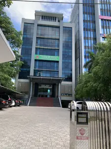 Bức ảnh chụp mặt tiền của một tòa nhà văn phòng hiện đại vào ban ngày. Đây là trụ sở của Ngân hàng Chính sách xã hội - Chi nhánh tỉnh Thanh Hóa.。Các dòng chữ trên các biển hiệu được ghi lại như sau:。1. Biển hiệu chính màu xanh lá cây trên tòa nhà: "NGÂN HÀNG CHÍNH SÁCH XÃ HỘI - CHI NHÁNH TỈNH THANH HÓA. THANH HOA PROVINCIAL BRANCH OF BANK FOR SOCIAL POLICIES. ĐỊA CHỈ: SỐ 38 ĐẠI LỘ LÊ LỢI, THÀNH PHỐ THANH HÓA - ĐIỆN THOẠI: 02373 888 850 - FAX: 02373 752 940". Trên biển hiệu có logo "VBSP".。2. Trên cổng xếp tự động bằng inox ở phía trước: Logo "PCG" và chữ "EU GATE".。3. Trên tòa nhà cao tầng bên cạnh có các biển hiệu: "SKY GROUP LOG... VẬN CHUYỂN CONTAINER NỘI... 0916.276.88..." và "PVC-TH".。Miêu tả cảnh vật và hoạt động:。- Địa điểm: Phía trước một tòa nhà văn phòng, cụ thể là một chi nhánh ngân hàng, nằm trong một khu đô thị. Tòa nhà có kiến trúc hiện đại với nhiều tầng và mặt tiền bằng kính.。- Hoạt động: Khung cảnh tĩnh lặng, không có hoạt động rõ rệt của con người. Nhiều ô tô đang đỗ trong bãi xe có mái che, cho thấy đây có thể là giờ làm việc.。- Các vật thể trong ảnh: Tòa nhà văn phòng, biển hiệu, một cổng xếp tự động bằng inox, nhiều xe ô tô đang đỗ, cây xanh, bậc tam cấp dẫn lên lối vào chính của tòa nhà.。（日本語訳）。日中に撮影された近代的なオフィスビルの正面の写真です。これは社会政策銀行タインホア省支店の本部です。看板の文字は以下の通りです：。1. 建物にある緑色のメイン看板：「NGÂN HÀNG CHÍNH SÁCH XÃ HỘI - CHI NHÁNH TỈNH THANH HÓA. THANH HOA PROVINCIAL BRANCH OF BANK FOR SOCIAL POLICIES. ĐỊA CHỈ: SỐ 38 ĐẠI LỘ LÊ LỢI, THÀNH PHỐ THANH HÓA - ĐIỆN THOẠI: 02373 888 850 - FAX: 02373 752 940」。看板には「VBSP」のロゴがあります。2. 正面にあるステンレス製の自動伸縮門扉には：「PCG」のロゴと「EU GATE」の文字があります。3. 隣の高層ビルには以下の看板があります：「SKY GROUP LOG... VẬN CHUYỂN CONTAINER NỘI... 0916.276.88...」と「PVC-TH」。風景と活動の描写：。- 場所：オフィスビルの前、具体的には都市部にある銀行の支店。建物は近代的な建築様式で、多層階建て、ガラス張りのファサードです。- 活動：静かな光景で、人々の明確な活動は見られません。屋根付きの駐車場に多くの車が駐車しており、就業時間中である可能性を示しています。- 写真の中の物体：オフィスビル、看板、ステンレス製の自動伸縮門扉、駐車している多数の自動車、緑の木々、建物の正面玄関に通じる階段。