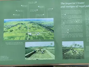 Đây là một bảng thông tin giới thiệu về khu di tích lịch sử, cụ thể là Thành nhà Hồ. Bảng có nền màu xanh lá cây, chứa cả văn bản và hình ảnh.。1. Chữ viết được ghi lại:。- Tiêu đề tiếng Anh: "The Imperial Citadel and vestiges of royal palace".。- Các chú thích địa điểm bằng tiếng Việt trên bản đồ ảnh: ① Đôi rồng đá, ② Hào thành, ③ La thành, ④ Di tích Nền Vua, ⑥ Hồ Dục Thúy, ⑦ Hồ Bơi Chải, ⑧ Hồ Dục Tượng, ⑨ Hồ Bán Nguyệt.。- Chú thích cho các ảnh nhỏ bên dưới: "Khai quật khu vực chính điện năm 2010", "...móng kiến trúc ...lộ tại Nền Vua 2011".。2. Mô tả cảnh quan và hoạt động:。- Địa điểm: Đây là một bảng chỉ dẫn tại một khu di tích lịch sử. Hình ảnh chính trên bảng là ảnh chụp từ trên cao của Thành nhà Hồ, cho thấy một khu vực rộng lớn với các công trình cổ, tường thành, hào nước, và được bao quanh bởi những cánh đồng lúa và làng mạc.。- Hoạt động: Các bức ảnh nhỏ hơn ở phía dưới ghi lại hoạt động khai quật khảo cổ. Trong ảnh, có thể thấy một nhóm người (có thể là nhà khảo cổ học và công nhân) đang làm việc trong một khu vực đã được đào lên. Một số người đội nón lá. Họ đang tiến hành đào, dọn dẹp và nghiên cứu tại hiện trường khai quật.。（日本語訳）。これは歴史遺跡、具体的には胡朝の城塞を紹介する案内板です。案内板は緑色の背景で、文章と写真の両方が含まれています。1. 記載されている文字：。- 英語のタイトル：「The Imperial Citadel and vestiges of royal palace」。- 写真地図上のベトナム語による地名注釈：①石龍一対、②城の堀、③羅城、④ネンヴア遺跡、⑥ズックトゥイ湖、⑦ボイチャイ湖、⑧ズックトゥオン湖、⑨バンギエット湖。- 下部の小さな写真のキャプション：「2010年正殿地区の発掘」、「...2011年ネンヴアで露出した...建築の基礎」。2. 景観と活動の説明：。- 場所：これは歴史遺跡にある案内板です。案内板のメイン写真は胡朝の城塞を上空から撮影したもので、古代の建造物、城壁、堀がある広大なエリアが写っており、水田や村々に囲まれています。- 活動：下部にある小さな写真には、考古学的な発掘活動が記録されています。写真では、一団の人々（考古学者や作業員の可能性がある）が掘り起こされたエリアで作業しているのが見えます。何人かはノンラーをかぶっています。彼らは発掘現場で掘削、清掃、調査を行っています。