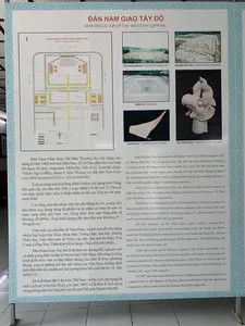 Đây là hình ảnh một bảng thông tin giới thiệu chi tiết về di tích Đàn Nam Giao Tây Đô, một phần của Di sản Thế giới Thành Nhà Hồ. Bảng thông tin này được đặt trong nhà, có nội dung bằng cả tiếng Việt và tiếng Anh, mô tả lịch sử, cấu trúc và các hiện vật liên quan đến đàn tế.。Nội dung trên bảng bao gồm:。1.  **Chữ viết:**。*   Tiêu đề chính: "ĐÀN NAM GIAO TÂY ĐÔ".。*   Tiêu đề sơ đồ: "SƠ ĐỒ CẤU TRÚC ĐÀN NAM GIAO".。*   Chú thích cho các hình ảnh: "TOÀN CẢNH ĐÀN NAM GIAO", "NỀN MÓNG KIẾN TRÚC", "GIẾNG VUA", "NGÓI ĐẦU ĐAO", "ĐẦU CHIM PHƯỢNG".。*   Nội dung văn bản tiếng Việt được ghi lại đầy đủ: "Đàn Nam Giao được Hồ Hán Thương cho xây dựng vào tháng 8 năm 1402 trên núi Đốn Sơn. Lễ tế Giao đầu tiên của triều Hồ được tổ chức cùng năm. Sách Đại Việt sử ký Toàn thư chép: “Nhâm Ngọ (1402), tháng 8, Hán Thương sai đắp đàn Nam Giao ở núi Đốn Sơn làm lễ tế Giao, đại xá thiên hạ”. Tính từ chân núi Đốn Sơn, Đàn tế được xây dựng trên 5 tầng nền giật cấp cao dần lên: Nền 1 (cao nhất) với độ cao 21,70m so với mực nước biển; nền 5 (thấp nhất) có độ cao 12m so với mực nước biển. Các tầng nền đàn được xây bó nền bằng đá vôi, móng nền đàn được xây dựng bằng đá phiến và đá phấn có màu đỏ son và màu vàng nhạt dày hơn 1m. Tổng diện tích mặt bằng đàn tế khoảng 30.000m², tổng khối lượng đất đào đắp ước khoảng 35 - 40 nghìn m³. Trên mặt các nền đàn tế Nam Giao, người xưa đã xây dựng nhiều loại kiến trúc khác nhau như: Tường đàn, sân đàn, đường Thần đạo, Viên đàn (nơi tế Trời), các nền đàn thờ đa thần, Trai Cung, Giếng Vua, Thần Khố (Kho tàng), Thần Trù (nhà Bếp)... Đàn Nam Giao Tây Đô là di tích còn tương đối nguyên vẹn cổ nhất trong lịch sử đàn tế Nam Giao Việt Nam. Đó cũng là công trình kiến trúc vừa có đặc điểm chung của đàn tế Giao phương Đông, vừa có những nét đặc sắc riêng của Việt Nam, khẳng định tinh thần dân tộc mạnh mẽ của vương triều Hồ cuối thế kỷ 14 - đầu thế kỷ 15. Di tích được Bộ Văn hóa, Thể thao và Du lịch xếp hạng Di tích Lịch sử Văn hóa Quốc gia năm 2007 và là khu di tích quan trọng trong cấu trúc tổng thể của Di sản Thế giới Thành Nhà Hồ."。2.  **Cảnh vật và đồ vật:**。*   **Địa điểm:** Một bảng thông tin được trưng bày, có thể ở trong một bảo tàng hoặc tại khu di tích.。*   **Hoạt động:** Không có hoạt động nào diễn ra; đây là một vật thể tĩnh.。*   **Đồ vật được chụp:** Bảng thông tin (biển chỉ dẫn) có chứa một sơ đồ cấu trúc của đàn tế, các bức ảnh chụp toàn cảnh khu di tích, nền móng, Giếng Vua, và các hiện vật khảo cổ như ngói lợp mái và đầu tượng chim phượng bằng đất nung.。（日本語訳）。これは、世界遺産「胡朝の城塞」の一部である西都南郊壇遺跡について詳しく紹介する案内板の画像です。この案内板は屋内に設置されており、ベトナム語と英語の両方で内容が記載され、祭壇の歴史、構造、関連する遺物について説明しています。案内板の内容は以下の通りです。1.  **文字:**。*   主な見出し：「西都南郊壇」。*   図の見出し：「南郊壇構造図」。*   写真のキャプション：「南郊壇全景」、「建築基礎」、「王の井戸」、「鬼瓦」、「鳳凰の頭部」。*   ベトナム語の本文全文：「南郊壇は、1402年8月に胡漢蒼によってドンソン山に建設されました。胡朝最初の郊祀（天を祀る儀式）は同年に執り行われました。『大越史記全書』には、『壬午（1402年）8月、漢蒼はドンソン山に南郊壇を築かせ、郊祀を行い、天下に大赦を行った』と記されています。ドンソン山の麓から数えて、祭壇は5層の段状の基壇の上に建てられており、徐々に高くなっています。第1基壇（最高）は海抜21.70m、第5基壇（最低）は海抜12mです。各層の基壇は石灰岩で擁壁が築かれ、祭壇の基礎は厚さ1m以上の朱色と淡黄色の粘板岩と白亜で造られています。祭壇の総敷地面積は約30,000平方メートル、掘削・盛土の総土量は約3万5千～4万立方メートルと推定されます。南郊壇の各基壇の上には、昔の人々は壇の壁、壇の庭、神道、圜壇（天を祀る場所）、多神を祀る各壇、斎宮、王の井戸、神庫（宝物庫）、神厨（厨房）など、さまざまな種類の建築物を建てました。西都南郊壇は、ベトナムの南郊壇の歴史において、最も古く、比較的完全な形で残っている遺跡です。それはまた、東洋の郊祀壇の共通の特徴と、ベトナム独自の特色を併せ持つ建築物であり、14世紀末から15世紀初頭にかけての胡朝の強い民族精神を裏付けています。この遺跡は2007年に文化・スポーツ・観光省によって国家歴史文化遺跡に指定され、世界遺産『胡朝の城塞』の全体構造における重要な遺跡地区です。」。2.  **風景と物:**。*   **場所:** 博物館または遺跡地区に展示されている案内板。*   **活動:** 何も行われていません。これは静止した物体です。*   **撮影された物:** 祭壇の構造図、遺跡地区の全景写真、基礎、王の井戸、そして屋根瓦やテラコッタ製の鳳凰の頭部像などの考古学的遺物を含む案内板（標識）。