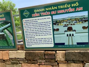 Bức ảnh chụp hai tấm biển thông tin màu xanh lá cây đặt trên một bức tường gạch cũ tại một khu di tích lịch sử. Tấm biển chính ở bên phải cung cấp thông tin về một nhân vật lịch sử, trong khi tấm biển bên trái chỉ nhìn thấy một phần.。**Chữ viết trên biển:**。1.  **Biển bên phải (đầy đủ):**。*   Tiêu đề: "DANH NHÂN TRIỀU HỒ - KIẾN TRÚC SƯ NGUYỄN AN"。*   Logo: "THE HO CITADEL - THÀNH NHÀ HỒ - DI SẢN VĂN HÓA THẾ GIỚI"。*   Nội dung: "Nguyễn An sinh năm 1381 tại Hà Nội, mang trong mình tài hoa trời phú. Năm 1397, ông có mặt trong kíp thợ khéo để xây dựng các công trình cung điện tuyệt tác nhà Trần, trong đó có thành An Tôn (Thành Nhà Hồ). Năm 1407, nhà Minh đã bắt ông cùng nhiều người có tài khác của đất Việt đưa sang Trung Quốc. Ông đã được giao làm tổng công trình sư - người chịu trách nhiệm tối cao cho công trình: thiết kế, quán sát, đôn đốc xây dựng Tử Cấm Thành ở Bắc Kinh. Tài năng của ông càng được bộc lộ rõ hơn thông qua cách vận chuyển những khối đá nguyên khối nặng đến 80 tấn về điêu khắc xây dựng Cố cung và tham gia trị thủy hệ thống sông Hoàng Hà."。*   Chú thích ảnh: "PHỎNG HOẠ 3D KIẾN TRÚC KINH THÀNH TÂY ĐÔ"。2.  **Biển bên trái (một phần):**。*   Tiêu đề: "...HỒ ...UNG"。*   Chú thích ảnh: "...TRỪNG - ÔNG TỔ SÚNG THẦN CÔNG"。**Mô tả cảnh vật và hoạt động:**。*   **Loại địa điểm:** Khu vực trưng bày thông tin ngoài trời tại một di tích lịch sử, cụ thể là Thành Nhà Hồ.。*   **Hoạt động:** Không có hoạt động nào của con người diễn ra. Các tấm biển được dựng lên để cung cấp thông tin lịch sử cho khách tham quan.。*   **Vật thể:**。*   Hai tấm biển thông tin lớn, có khung viền hoa văn, màu xanh lá cây với chữ màu trắng và vàng.。*   Một bức tường thấp được xây bằng những viên gạch đá cổ, có kích thước và màu sắc không đồng đều.。*   Trên biển bên phải có một hình ảnh phỏng dựng 3D kiến trúc của một tòa thành cổ.。*   Trên biển bên trái có hình ảnh một khẩu súng thần công cổ.。*   Phía sau là cây cối xanh tươi.。（日本語訳）。歴史遺跡にある古いレンガの壁の上に設置された、2枚の緑色の案内板を写した写真です。右側の主要な案内板は歴史上の人物に関する情報を提供しており、一方、左側の案内板は一部しか見えません。**案内板の文字：**。1.  **右側の案内板（全文）：**。*   タイトル：「胡朝の名人 - 建築家グエン・アン」。*   ロゴ：「THE HO CITADEL - 胡朝の城 - 世界文化遺産」。*   内容：「グエン・アンは1381年にハノイで生まれ、天賦の才能を持っていました。1397年、彼は陳朝の傑作である宮殿建築、その中にはアン・トン城（胡朝の城）も含まれますが、その建設のために腕利きの職人チームの一員となりました。1407年、明朝は彼とベトナムの他の多くの才能ある人々を捕らえ、中国へ連れて行きました。彼は総工事師に任命され、北京の紫禁城の建設において、設計、監督、督促という最高の責任を負うことになりました。彼の才能は、故宮を建設・彫刻するために重さ80トンにもなる一枚岩の石塊を運搬する方法や、黄河水系の治水に参加したことを通して、より一層明らかになりました。」。*   写真キャプション：「西都京城の建築3D再現図」。2.  **左側の案内板（一部）：**。*   タイトル：「...HỒ ...UNG」。*   写真キャプション：「...TRỪNG - 神功砲の始祖」。**風景と活動の説明：**。*   **場所の種類：**歴史遺跡、具体的には胡朝の城にある屋外情報展示エリア。*   **活動：**人間の活動は行われていません。案内板は、来訪者へ歴史情報を提供するために設置されています。*   **物体：**。*   2枚の大きな案内板。模様の入った縁取りがあり、緑色地に白と黄色の文字が書かれています。*   古い石レンガで造られた低い壁。石の大きさと色は不揃いです。*   右側の案内板には、古い城の建築3D再現図があります。*   左側の案内板には、古い神功砲の画像があります。*   後方には青々とした木々があります。