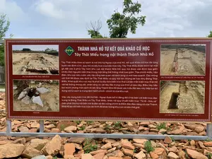 Đây là hình ảnh chụp một tấm biển thông tin lớn tại một khu di tích khảo cổ học ngoài trời, cụ thể là khu vực Tây Thái Miếu trong nội thành Thành Nhà Hồ. Tấm biển có nền màu nâu, chữ trắng, được đặt trên một khung kim loại. Phía sau tấm biển là cây cối và bầu trời. Phía trước và dưới chân biển là các mảnh gạch và đá vỡ, là một phần của di tích khảo cổ.。Nội dung văn bản trên biển được ghi lại như sau:。Tiêu đề chính: THÀNH NHÀ HỒ TỪ KẾT QUẢ KHẢO CỔ HỌC。Tiêu đề phụ: Tây Thái Miếu trong nội thành Thành Nhà Hồ。Nội dung chi tiết: "Tây Thái miếu theo sử sách là nơi thờ họ Ngoại của nhà Hồ, kết quả Khảo cổ học đã từng bước xác định vị trí, quy mô và cấu trúc của kiến trúc này. Tây Thái Miếu được bố trí tại một gò đất cao ở phía Tây nam khu vực nội thành Nhà Hồ; quy mô được xác định bao gồm nhiều đơn nguyên kiến trúc trong một tổng thể thống nhất bao gồm: Tòa chính miếu, hậu điện, khu vực sân vườn, các lớp cổng tam quan và hành lang có mái bao quanh. Các móng cột thời Hồ được xác định tại Tây Thái Miếu có quy mô lớn nhưng bé hơn khu Đông Thái Miếu. Khai quật khu vực này là phát lộ dấu tích kiến trúc thời Lê bên trên kiến trúc thời Hồ với hệ thống móng cột, chân tảng và vật liệu đặc trưng của thời Lê sau này. Điều này tiếp tục minh chứng một cách rõ nét rằng Thành Nhà Hồ được các triều đại sau này tiếp tục sử dụng với tư cách là trung tâm hành chính - chính trị của khu vực.。Việc xây dựng kiến trúc để thờ Nội - Ngoại được bố trí đăng đối ở hai bên với kiến trúc đặc trưng là Đông Thái Miếu và Tây Thái Miếu, khác với quy chuẩn kiến trúc "Tả tổ - Hữu xã" (bên phải thờ họ nội bên trái là đàn xã tắc) cũng chính là điểm độc đáo riêng có của Thành Nhà Hồ so với kiến trúc của các kinh đô khác trong khu vực và trên thế giới."。Trên biển còn có 4 bức ảnh chụp các địa điểm khai quật với các chú thích:。1. DẤU TÍCH BÓ NỀN KIẾN TRÚC THỜI LÊ SƠ。2. GIẾNG ĐÁ。3. DẤU TÍCH BÓ NỀN VÀ MÓNG CỘT KIẾN TRÚC TẠI TÂY THÁI MIẾU。4. CHI TIẾT MÓNG CỘT THỜI HỒ TẠI TÂY THÁI MIỀU。（日本語訳）。これは屋外の考古学遺跡、具体的には胡朝の城の内城にある西太廟地区の大きな案内板を撮影した写真です。案内板は茶色の背景に白文字で、金属製のフレームの上に設置されています。案内板の後ろには木々と空が見えます。案内板の前と足元には、考古学遺跡の一部であるレンガや割れた石の破片があります。案内板の文面は以下の通りです。主な見出し：考古学的成果から見た胡朝の城。副見出し：胡朝の城の内城にある西太廟。詳細な内容：「西太廟は史書によれば胡朝の母方の祖先を祀る場所であり、考古学の成果によってこの建築物の位置、規模、構造が段階的に特定されてきました。西太廟は胡朝の城の内城地区の南西にある高台に配置されています。その規模は、正廟、後殿、庭園区域、幾層もの三関門、そして周囲を囲む屋根付きの回廊を含む、統一された全体像の中に多くの建築単位が含まれていると特定されています。西太廟で確認された胡朝時代の柱の基礎は大規模ですが、東太廟地区のものよりは小さいです。この地域の掘削により、胡朝時代の建築物の上に、後の黎朝時代の特徴的な柱の基礎、礎石、建材のシステムを持つ黎朝時代の建築遺跡が発見されました。このことは、胡朝の城が後の王朝によっても地域の行政・政治の中心として引き続き使用されたことを明確に証明しています。父方・母方の祖先を祀るための建築物を、東太廟と西太廟という特徴的な建築物で両側に対称的に配置したことは、『左祖右社』（右に父方の祖先を祀り、左に社稷壇を置く）という建築規範とは異なり、地域内および世界の他の都の建築物と比較して、胡朝の城ならではのユニークな点でもあります。」。案内板には、発掘場所を撮影した4枚の写真と以下のキャプションもあります。1. 黎初朝時代の建築基礎の痕跡。2. 石の井戸。3. 西太廟における建築基礎と柱の基礎の痕跡。4. 西太廟における胡朝時代の柱の基礎の詳細