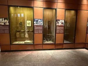 博物館の展示室のようで、ガラスケースの中に遺物が展示され、その横に説明文のパネルが設置されています]