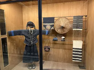 ガラスケース内に、黒を基調とした民族衣装を着たマネキンと、壁の棚に陳列された布製品、編笠、帽子などが展示されている