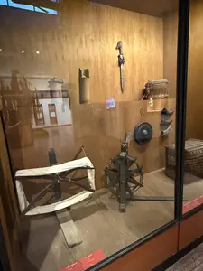 ガラスケース内に、木製の糸巻き車、綛揚げ機、籠、刃物などの民具が展示されている