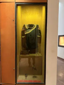 ガラスケースの中に、襟と袖口に模様が施された黒い上着が展示されている。画像には判読可能な文字は一切含まれていない