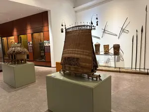 Trang phục Ê Đê - Mẹ trong lễ cúng chữa bệnh。Trang phục của người Ê Đê được làm từ vải dệt thủ công, thường có màu chàm hoặc đen, được trang trí bằng các hoa văn hình học và các hạt cườm.。Trong lễ cúng chữa bệnh, người mẹ mặc trang phục đặc biệt để cầu nguyện cho con cái của mình. Trang phục này thường có màu sắc tươi sáng và được trang trí công phu hơn so với trang phục hàng ngày. Nó thể hiện sự tôn kính và hy vọng vào sự chữa lành của các vị thần. Các phụ kiện đi kèm như vòng cổ, vòng tay và khuyên tai cũng được sử dụng để tăng thêm vẻ đẹp và ý nghĩa tâm linh. Đây là một phần quan trọng trong văn hóa và tín ngưỡng của người Ê Đê.。（日本語訳）。エデ族の衣装 - 病気治癒の儀式における母親。エデ族の衣装は手織りの布から作られ、通常は藍色か黒色で、幾何学模様やビーズで装飾されています。病気治癒の儀式では、母親は自分の子供のために祈る特別な衣装を着用します。この衣装は通常、日常着よりも鮮やかな色で、より精巧に装飾されています。それは神々による癒やしへの敬意と希望を表しています。ネックレス、ブレスレット、イヤリングなどのアクセサリーも、美しさと精神的な意味を高めるために使用されます。これはエデ族の文化と信仰における重要な部分です。