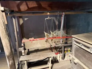 画像には文字が含まれていません。木製の古い織機が展示されています