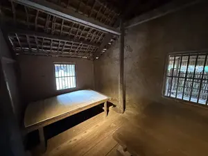 土壁の薄暗い部屋が写っている。壁際には木製の寝台が一つ置かれ、壁には鉄格子のようなものが入った窓が二つある