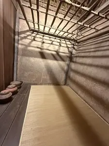 [竹か木で組まれた格子状の天井があり、その影が壁や床に落ちている室内