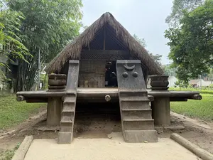 [画像には、茅葺き屋根を持つ高床式の木造建築物が写っている