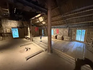 竹と木で造られた高床式の家屋の内部。土間と、床が張られた居住空間がある。壁には赤い布が掛けられている