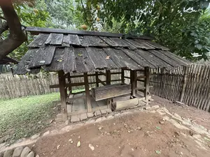 木製の板葺き屋根がある小屋と、その中に設置された水力で動かす木製の臼